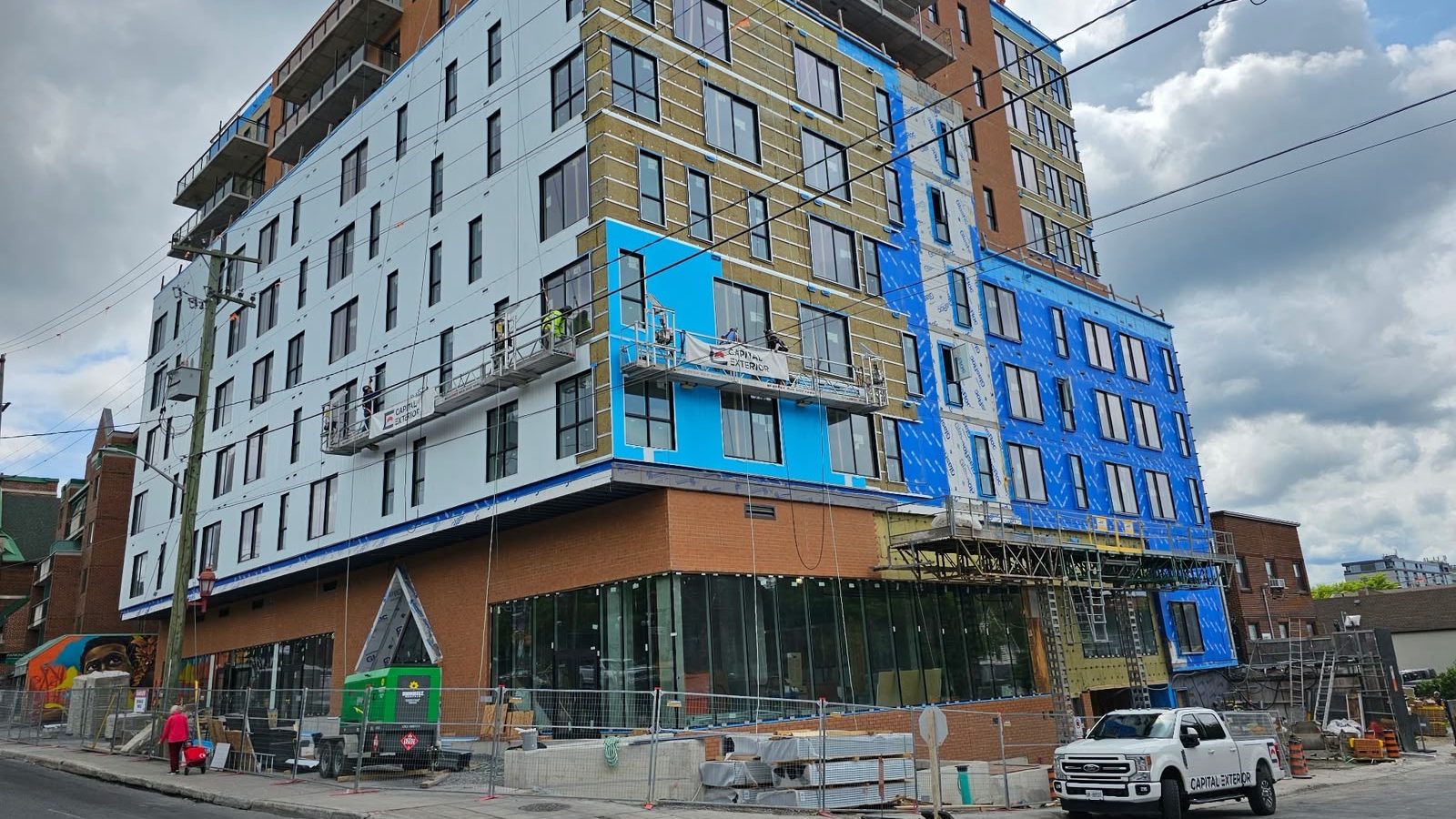 A swing-stage crew installing a continuous air and vapour barrier membrane on a mid-rise building.